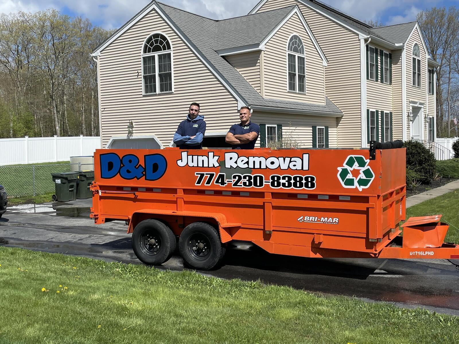 D&D Junk Removal crew standing with branded trailer in front of a Worcester County home